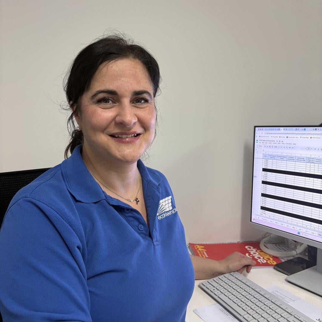 Claudia from EcoKleen Solar seated at her desk working on scheduling spreadsheets at a computer