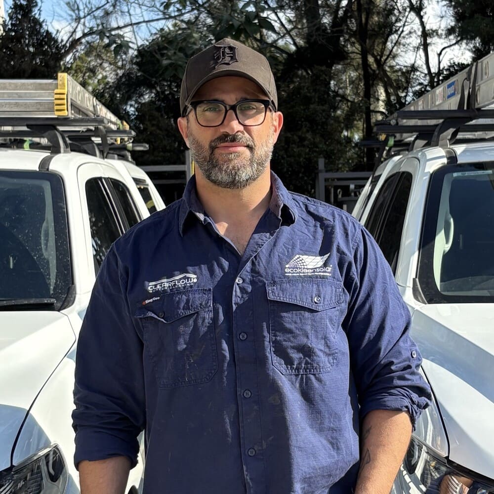 David from EcoKleen Solar standing between two work vehicles in outdoor daylight